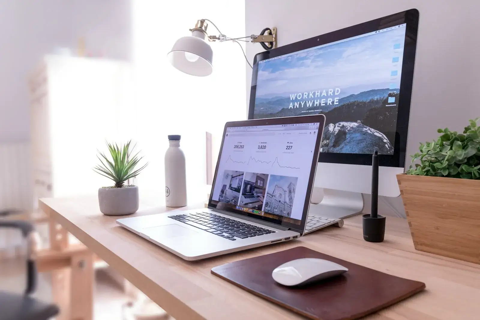 Bureau lumineux avec un grand écran et un ordinateur portable affichant des pages de site internet