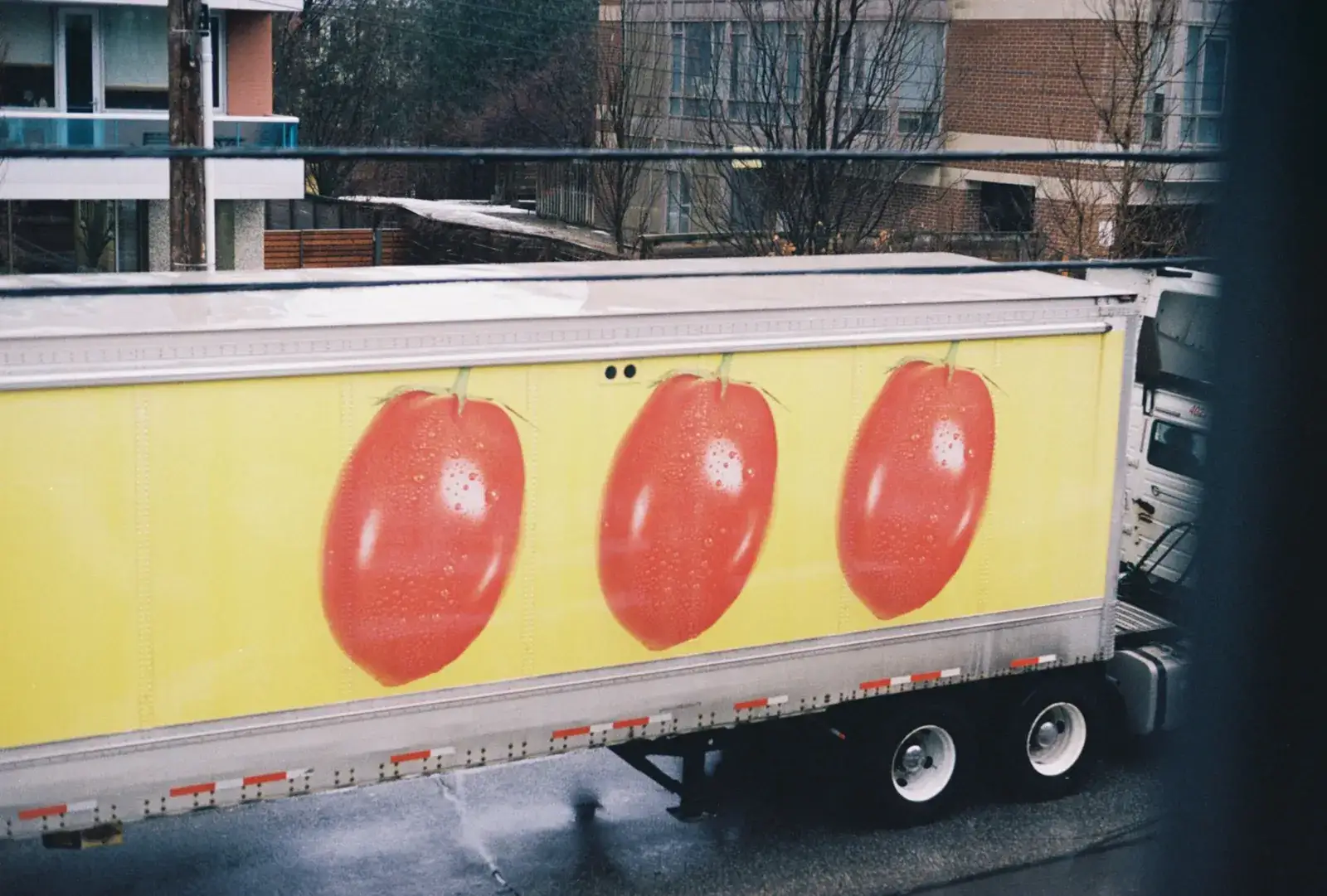 Remorque de camion jaune décorée de trois grosses tomates rouges
