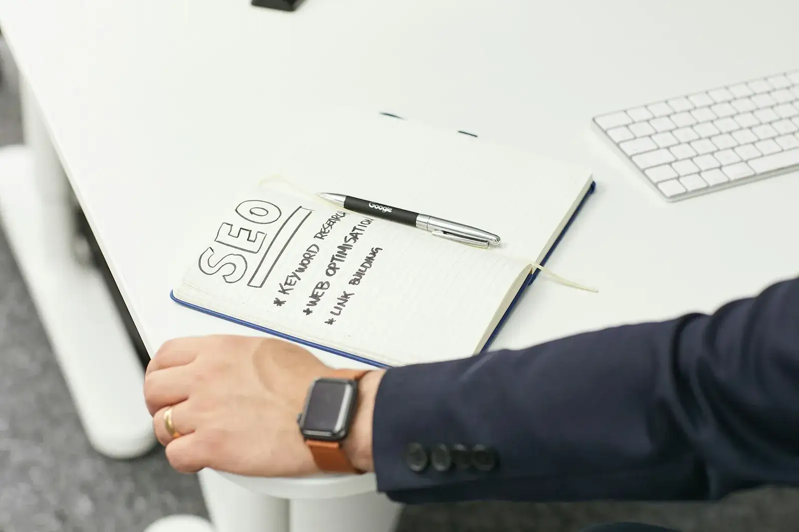 Carnet portant « SEO » et des mots-clés écrits à la main, devant un clavier