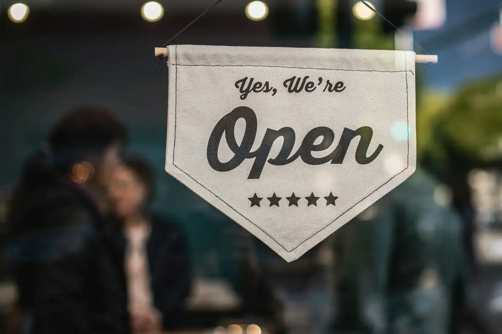 Fanion en toile « Yes, We’re Open » orné de cinq étoiles, suspendu dans une vitrine