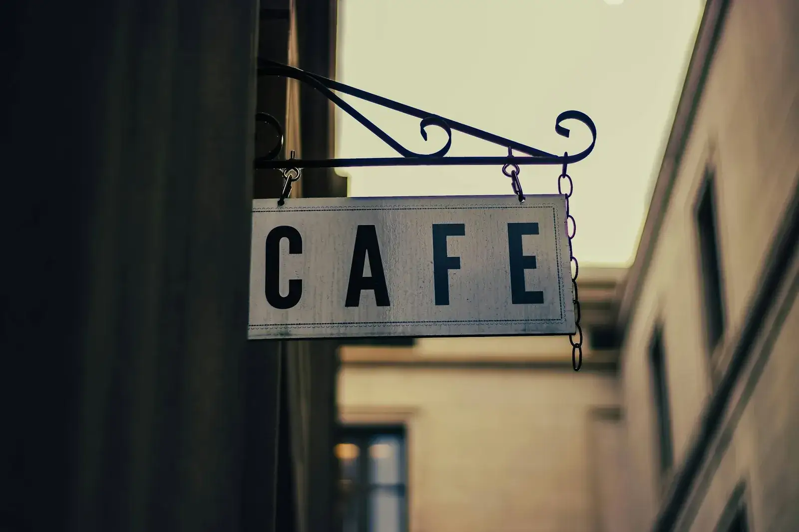 Enseigne drapeau « Café » suspendue à une potence en fer forgé