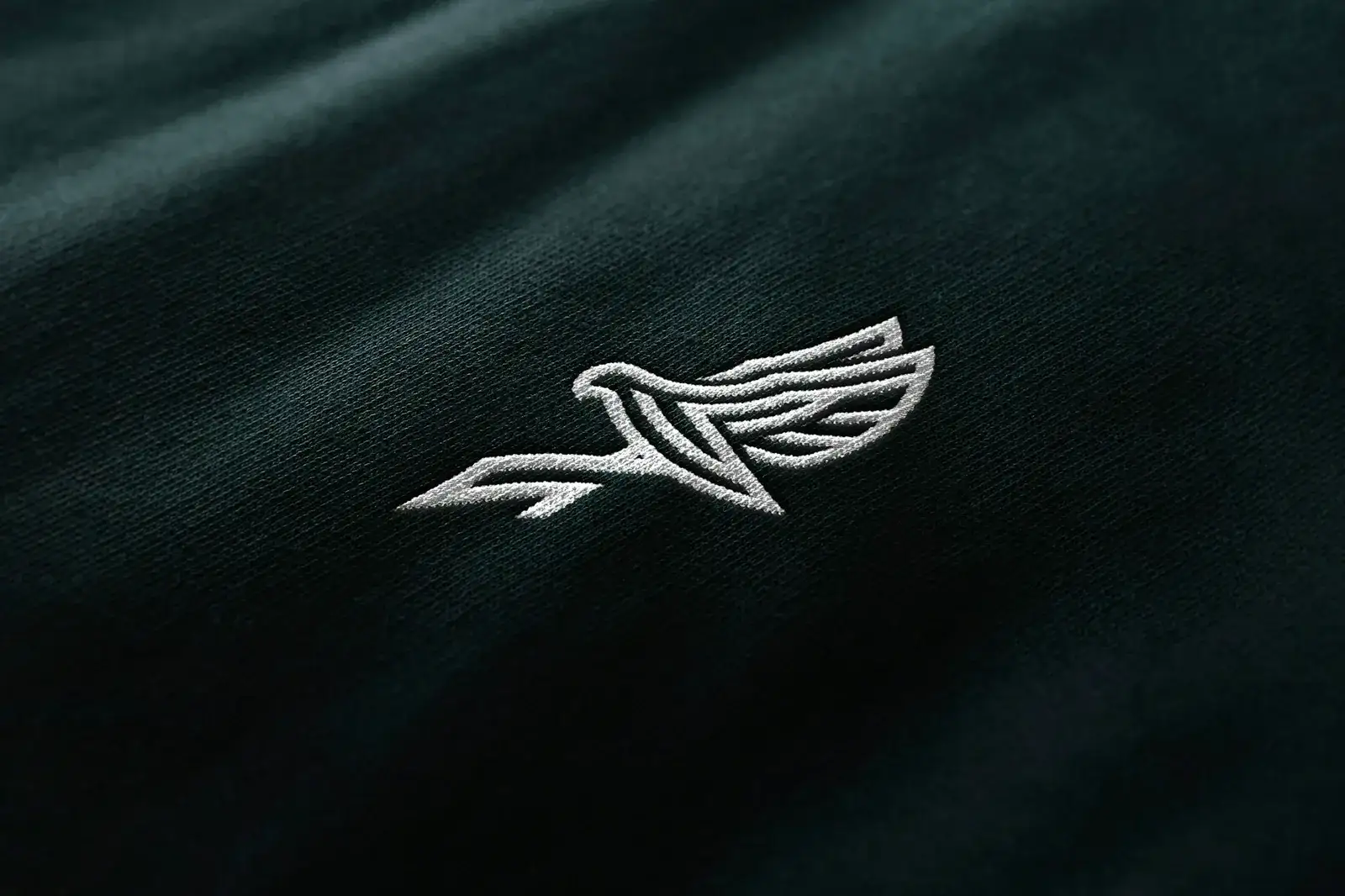 Logo d’oiseau brodé en fil blanc sur un vêtement noir